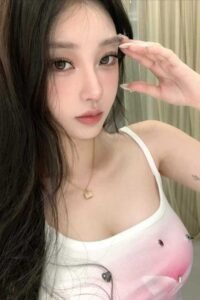 Portrait of a young woman with long dark hair, wearing a white tank top.