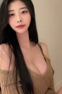 Attractive young woman with long black hair, wearing a brown sweater.