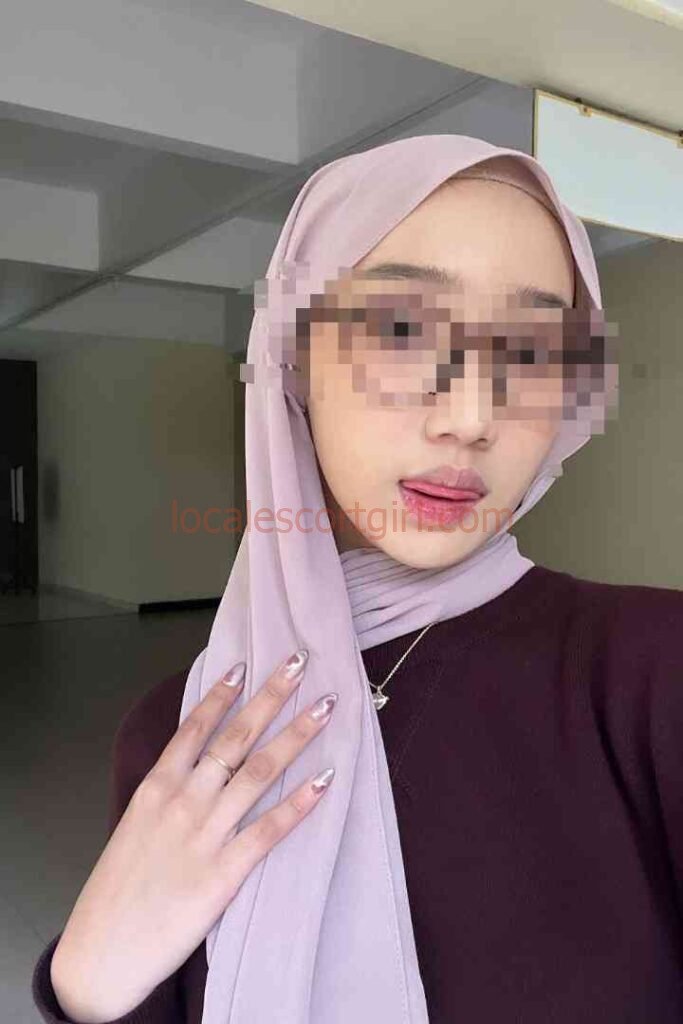 Kesya, a young Malay woman with a hijab and sunglasses, offers a playful expression.